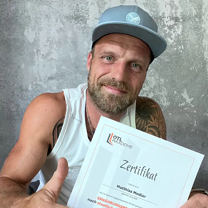 Ernährungsberater Zertifikat (Englisch) Unser Kunde Matthias hält sein Zertifikat der Ernährungsberater-Lizenz mit einem Daumen hoch in die Kamera.