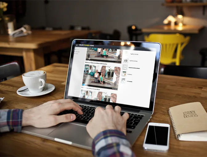 Foto eines Kunden, der in einem Café sitzend ganz flexibel auf seinem Laptop die Inhalte der Yoga-Ausbildung erlernt