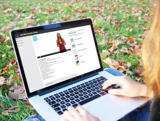 Kundin sitzt in der Natur und lernt ganz flexibel mit dem Laptop auf dem Schoß Inhalte ihrer Pilatestrainer-Ausbildung im Online Campus