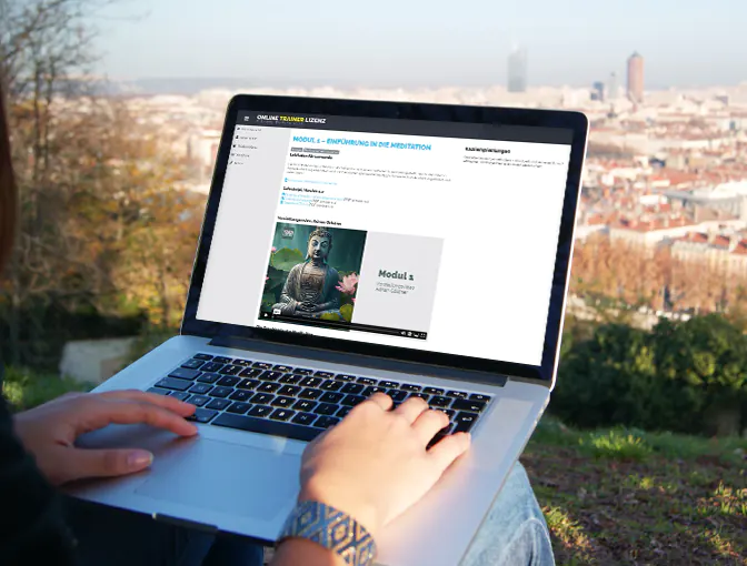Foto einer Person, die in der Natur mit ihrem Laptop sitzt und Inhalte der Meditationsausbildung im Online Campus lernt