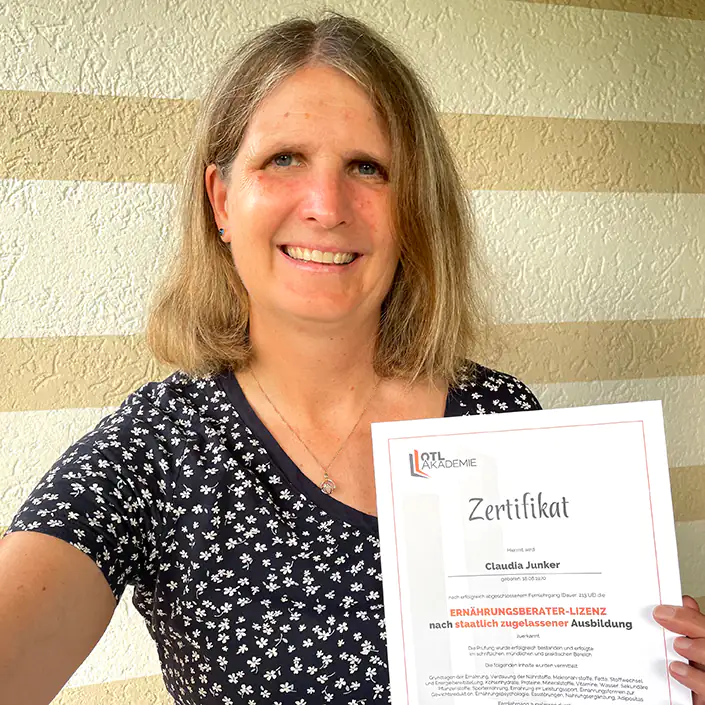 Ernährungsberater Zertifikat (Englisch) Kundin Claudia hält stolz das Zertifikat ihrer bestandenen Ernährungsberater-Lizenz in die Kamera.