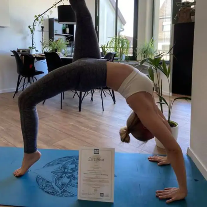 Unsere Kundin Frauke praktiziert Yoga in der Urdhva Dhanurasana Haltung und vor ihr steht ihr Zertifikat zur bestandenen Yogalehrer-Ausbildung
