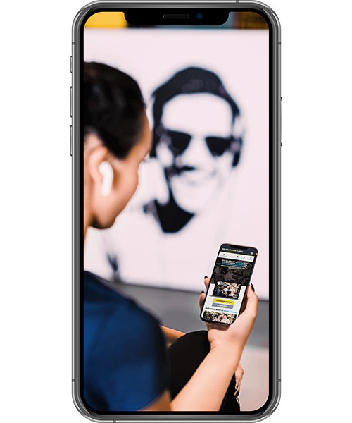 Smartphone-Rahmen um eine Szene, in der eine Frau mit AirPods ein Smartphone hält, mit welches sie auf unserer Website unterwegs ist;  im Hintergrund unscharf ein Porträt eines Mannes mit Sonnenbrille
