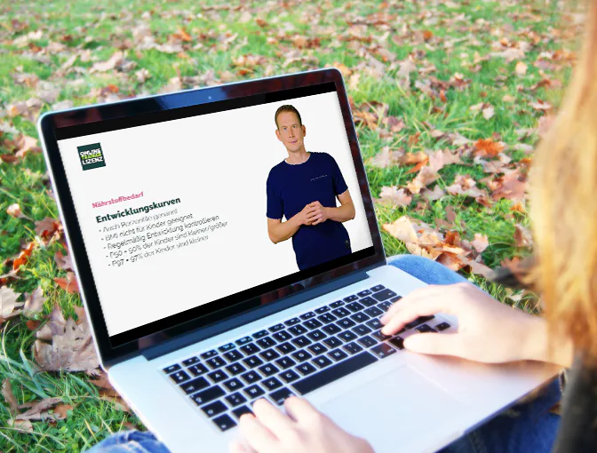 Kundin sitzt in der Natur und lernt ganz flexibel mit dem Laptop auf dem Schoß Inhalte ihrer Ausbildung zum Ernährungsberater für Kinder und Jugendliche im Online Campus