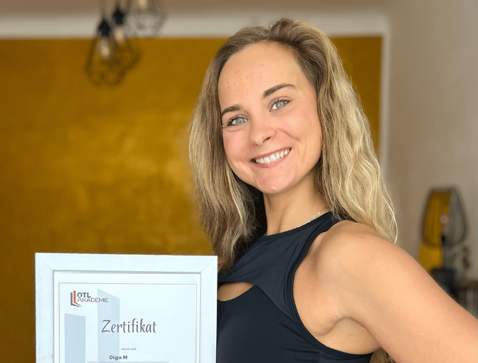 Absolventin der Fitnesstrainer B Lizenz Ausbildung zeigt ihr Zertifikat